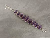 Top view of sterling silver bracelet showing nine faceted amethyst stones and toggle clasp