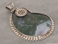 Front view showing moss agate cabochon, silver bezel and floral accent