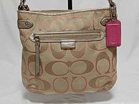 Front view of Coach metallic khaki jacquard crossbody bag with pink hangtag