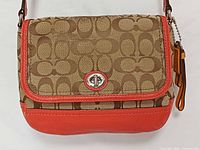 Front view of Coach khaki signature and vermillion leather crossbody bag showing turn-lock flap and hang tag