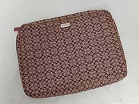 Front view of Coach purple Signature jacquard laptop sleeve, showing pattern and Coach plaque