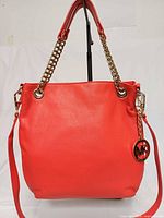 Front view of orange Michael Kors Jet Set bag showing chain handles and MK charm