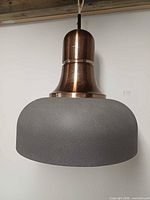 Full front view of pendant showing grey textured shade and copper-tone neck