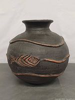 Front view showing spherical form, neck, and carved fish with wave band