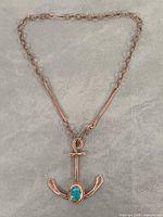 Front view of copper-tone anchor pendant necklace with blue-green cabochon stone on link chain
