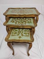 Three nesting tables stacked, showing painted tops