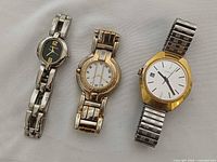 Three wristwatches laid flat showing dials and bracelets
