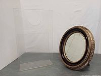 Lucite magazine holder and oval ornate mirror on display