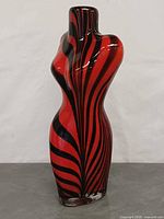 Front view of red and black striped female torso glass vase