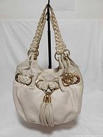 Front view of ivory leather Michael Kors Fulton hobo with braided handles, tassel, gold-tone rings