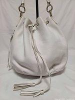 Front view of white leather bucket hobo bag with drawstring and tassels