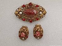 Front view of brooch and earrings showing design and stones