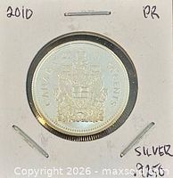 Coin in cardboard holder showing reverse Canadian coat of arms with date 2010