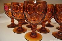 Close view of amber pressed glass goblets showing hubnail pattern and stem detail