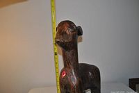 Front view showing carved wooden llama with measuring tape indicating height
