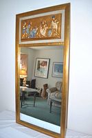 Full view of rectangular gilt mirror showing relief panel and glass