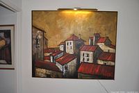 Front view of framed Mediterranean village scene painting on wall
