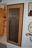 Full view of framed wood relief wall art hung on wall