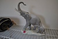 Full view of Lladro glossy gray porcelain elephant and calf figurine on white shelving