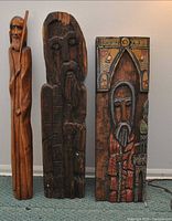 Front view of three carved wooden figures standing side by side