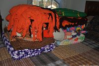 Stack of nine assorted hand-knitted afghans displaying colors and patterns