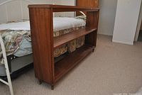 Overall view of walnut veneer bookshelf placed at bed foot