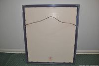 Rear view of framed artwork showing backing and hanging wire