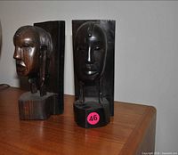Front view of both carved wood head bookends on tabletop
