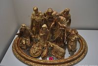 Front view of all gold resin nativity figures arranged on gilt mirror tray