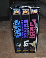 Spines of three Star Wars Trilogy VHS tapes inside slipcase showing titles, character images and THX logos