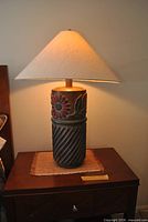 Front view of ceramic table lamp with beige shade on nightstand showing base design