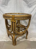 front view of bamboo rattan table showing glass top and lattice shelf