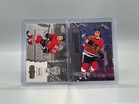 Front view of both cards in plastic holders, showing designs and condition