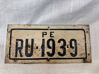 Front view of license plate showing PE RU-1939 text, mounting holes and wear