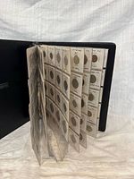 Binder partially open showing multiple pages of coin holders