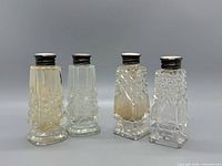Front view of four cut glass shakers