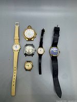 All six wristwatches laid out showing fronts and straps