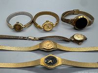 Front view of six wristwatches showing faces, bands and finishes