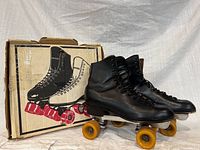 Pair of Dominion Marathon skates on metal plates with yellow wheels beside original box