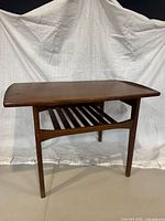 Perspective view of teak side table showing surfboard top and slatted shelf