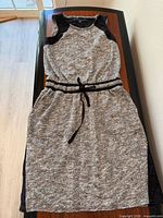 Full view of grey jersey dress laid flat showing overall style, drawstring waist and pockets