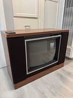 Front view showing screen, bezel, speakers, and remote on top