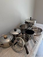 Group shot of all stainless pots, pans, lids and insert