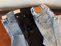 Waistbands and rear pockets showing Everlane and Levi’s branding on three jeans