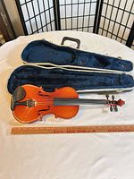 Violin with case open showing interior and size reference ruler
