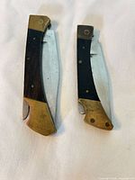 Both folding knives partially open showing blade profiles and handle materials