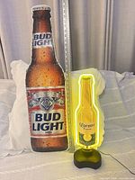 Corona neon lamp and Bud Light metal sign side by side for size context