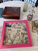 Lot overview showing wooden jewelry box, Russian doll decanter and closed pink display case