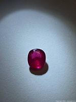 Top-down view of blood-red ruby under direct light displaying color and facet layout