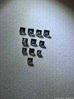 Group of square princess-cut sapphires arranged in rows on neutral background